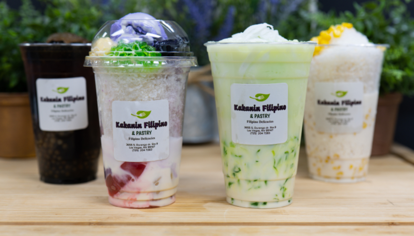 Kakanin Filipino's own bottled drinks lined up on a wooden counter: a dark drink, halo-halo, a pandan drink and a mango drink