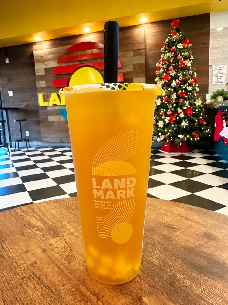 Mango Mania fruit tea held up inside the cafe in front of the Landmark logo