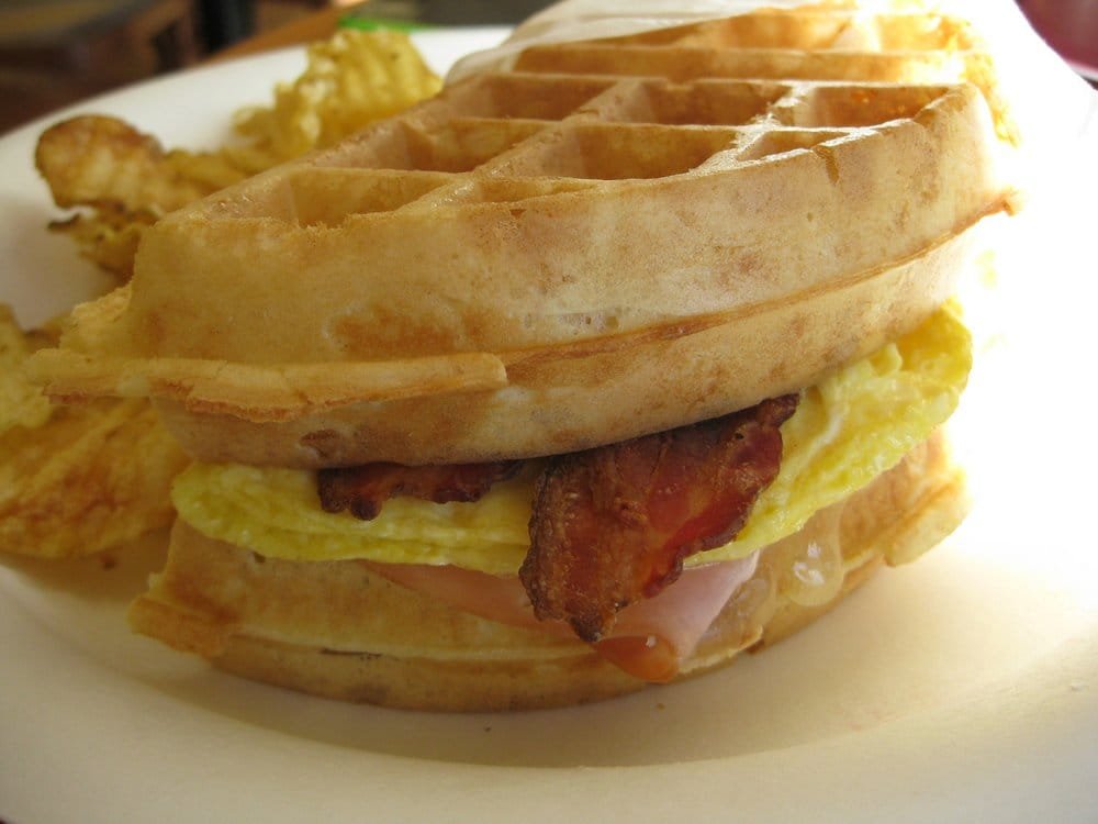 Close-up of our breakfast waffle sandwich layered with ham, bacon, egg and melted cheese