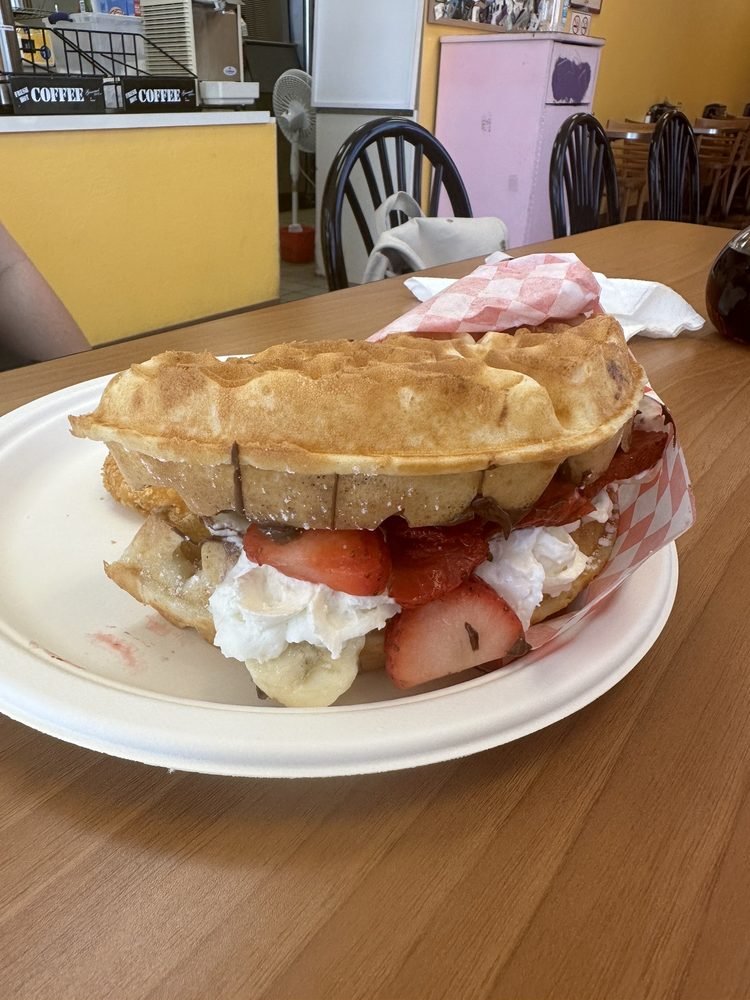 Fruit Nutella waffle sandwich filled with strawberries, banana and whipped cream